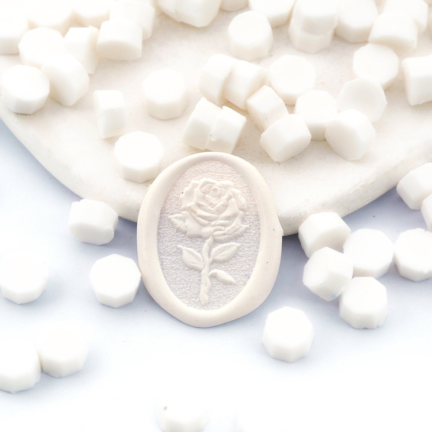 Some white wax beads placed on white cushion and cloth, and an wax seal created with them.