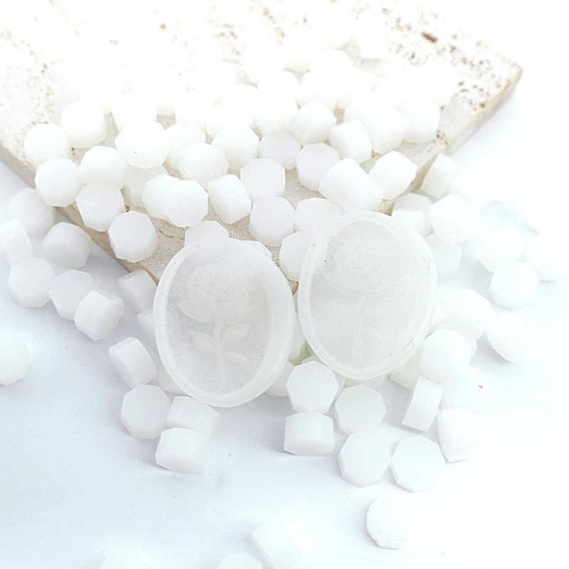 Some translucent white wax beads placed on white cushion and cloth, and an wax seal created with them.