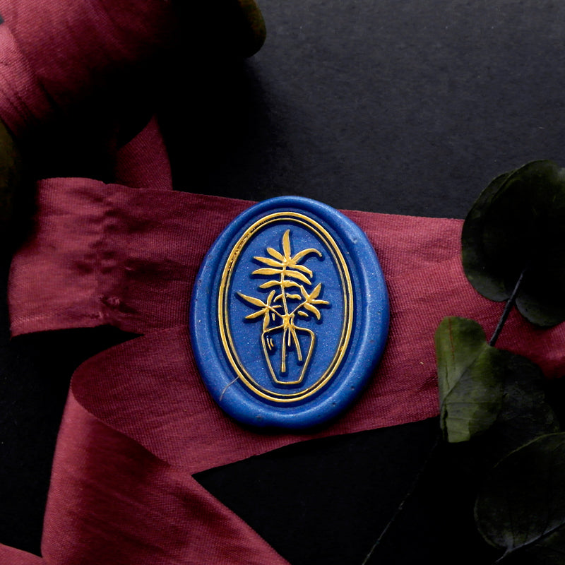Wax Seal Stamp, created an oval blue wax seal on a red ribbon with flower vase plant design .