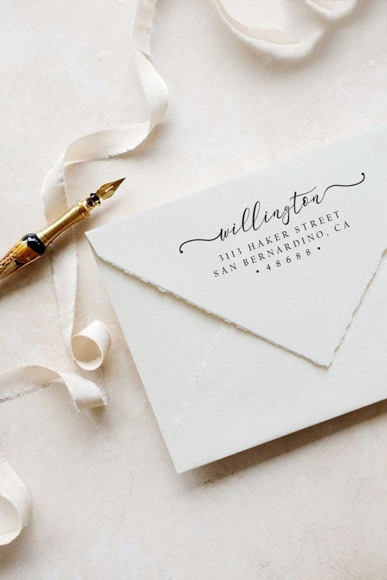A personalized self inking address stamp, customized with your name and address, stamped on the white envelop to save your time of hand writing, beside it, a ribbon is waiting for packing the gift.