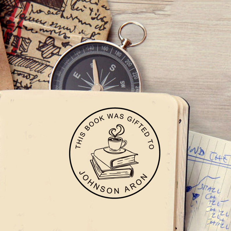 A book stamp in round, the top is text -This book was gifted, the centre is graphic of A cup of coffee on two books, the bottom is to custom your name.