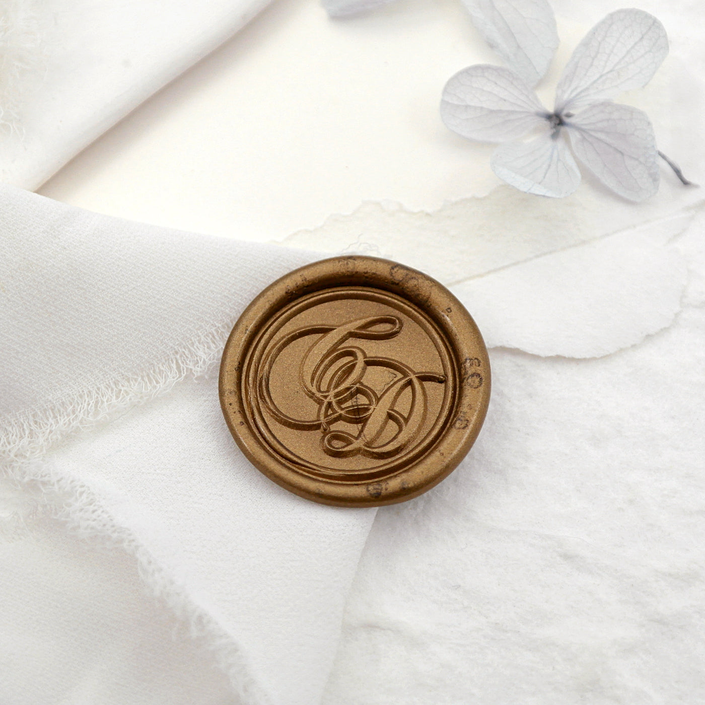A wax seal with personalized calligraphy initials on the white cloth.