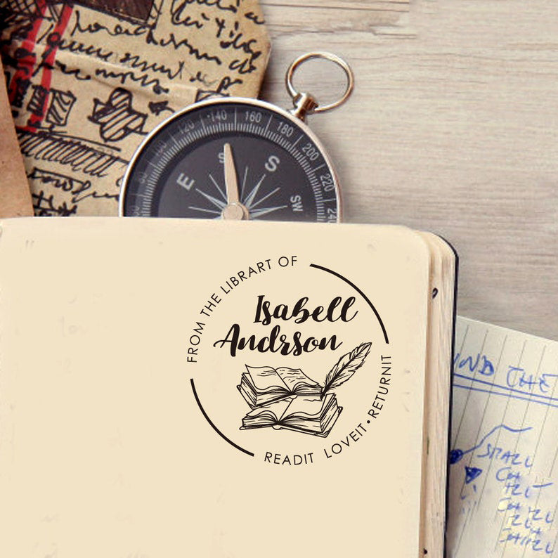 A personalized book stamp, shaped like round, the center is graphic of books and feather and custom your name, surrounded with words from the library of and read it. love it. return it.