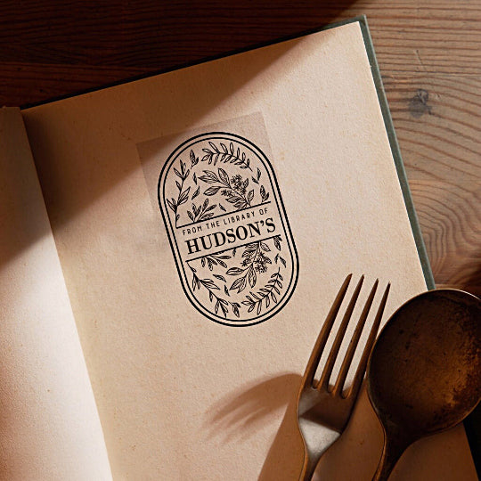 A personalized book stamp in oval, surrounded with leaves, the centre is to custom your library name.