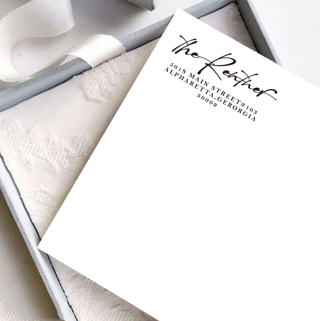 A personalized self inking address stamp, customized with your shop name and address, stamped on the white card, a gift box is under it.