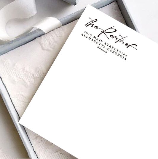 A personalized self inking address stamp, customized with your shop name and address, stamped on the white card, a gift box is under it.