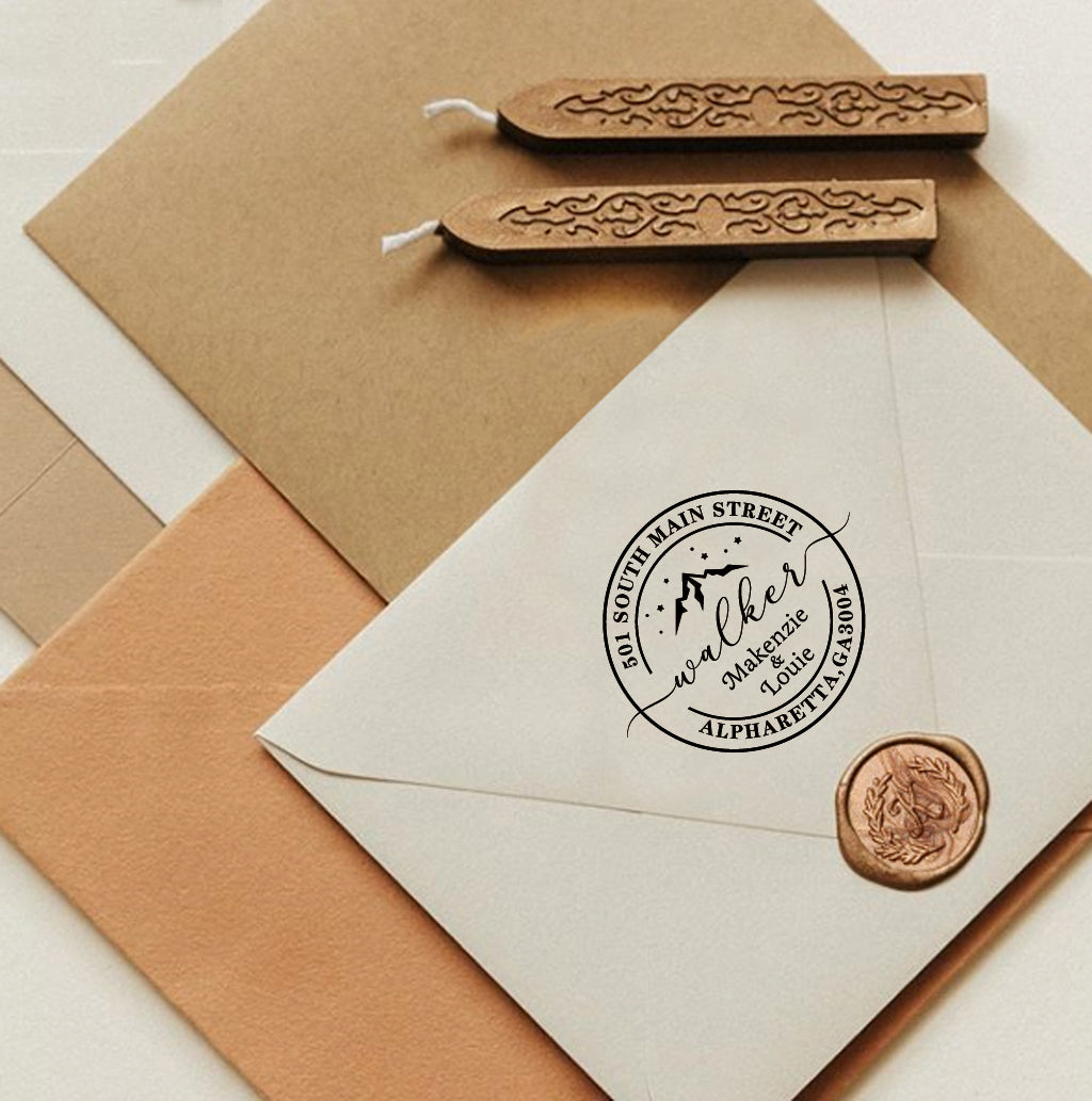 A personalized self inking return address stamp, customized with your name, address and mountain, stamped on the white envelope, beside it, sealing wax is creating a wax seal on the mail.