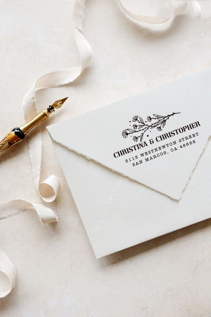 A personalized self inking address stamp, customized with your name, address and flower, stamped on the white envelop, beside it, a ribbon is waiting for packing the gift.