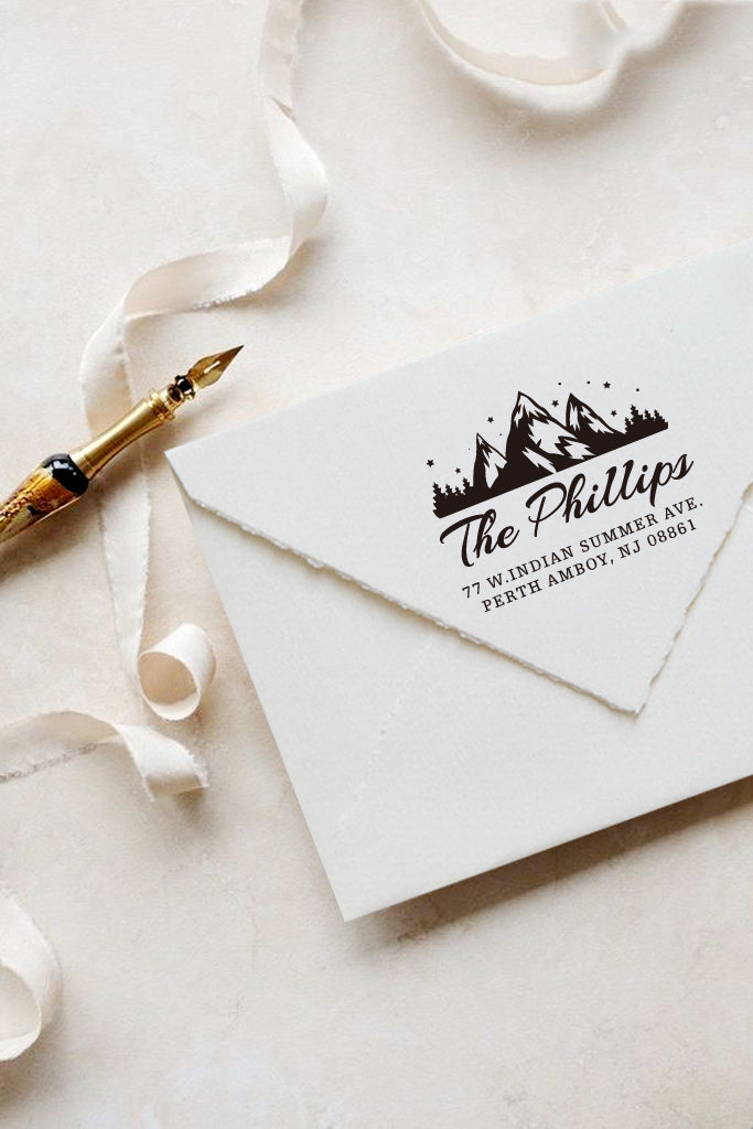 A personalized self inking address stamp, customized with your mountain logo name and address, stamped on the white envelop, beside it, a ribbon is waiting for packing the gift.