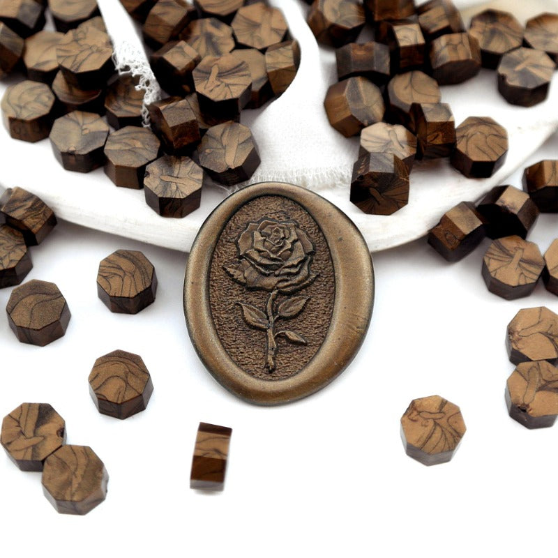 Some antique bronze wax beads placed on white cushion and cloth, and an wax seal created with them.