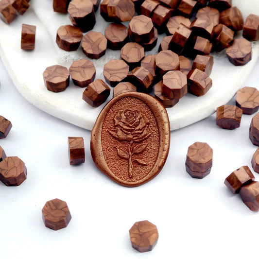 Some red copper wax beads placed on white cushion and cloth, and an wax seal created with them.