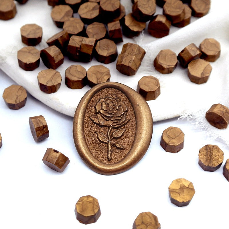 Some bronze wax beads placed on white cushion and cloth, and an wax seal created with them.