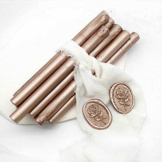 Sealing Wax Sticks in champagne gold with white wedding packing cloth wrapped, beside them, two rose flower pattern wax seals samples created.