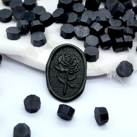 Some black wax beads placed on white cushion and cloth, and an wax seal created with them.