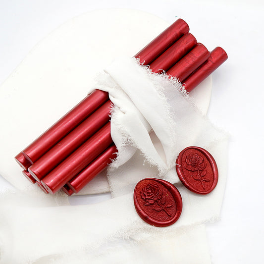 Sealing Wax Sticks in Metallic Rich Red with white wedding packing cloth wrapped, beside them, two rose flower pattern wax seals samples created.