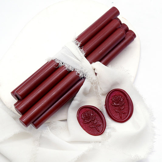 Sealing Wax Sticks in Burgundy Red with white wedding packing cloth wrapped, beside them, two rose flower pattern wax seals samples created.