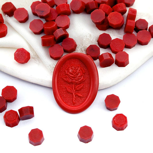 Some Classic Red wax beads placed on white cushion and cloth, and an wax seal created with them.