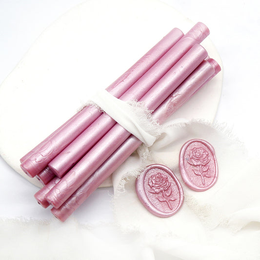 Sealing Wax Sticks in Pearlescent Dusty Rose Pink with white wedding packing cloth wrapped, beside them, two rose flower pattern wax seals samples created.