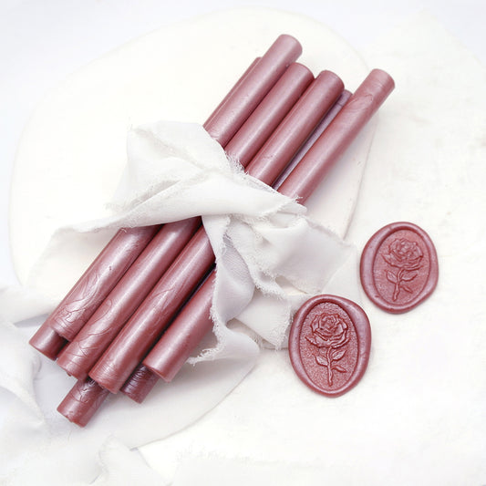 Sealing Wax Sticks in Pearlescent Dusty Rose Pink with white wedding packing cloth wrapped, beside them, two rose flower pattern wax seals samples created.