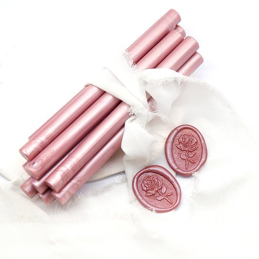Sealing Wax Sticks in Rose Gold Pink with white wedding packing cloth wrapped, beside them, two rose flower pattern wax seals samples created.