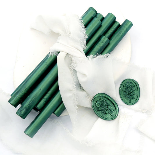 Sealing Wax Sticks in Metallic Forest Green with white wedding packing cloth wrapped, beside them, two rose flower pattern wax seals samples created.