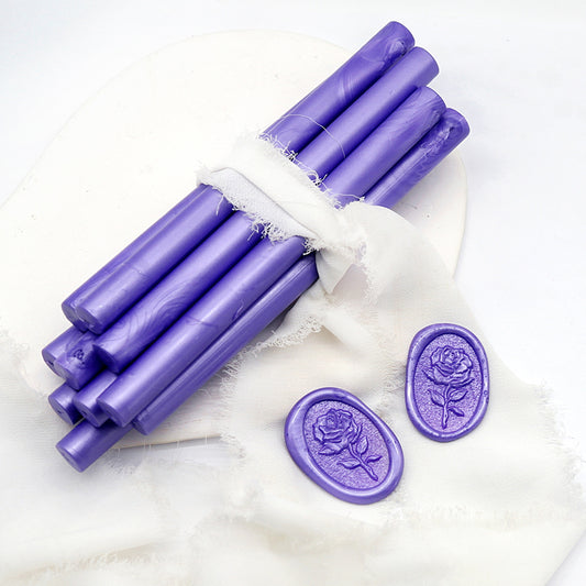 Sealing Wax Sticks in Pearlescent Lavender with white wedding packing cloth wrapped, beside them, two rose flower pattern wax seals samples created.