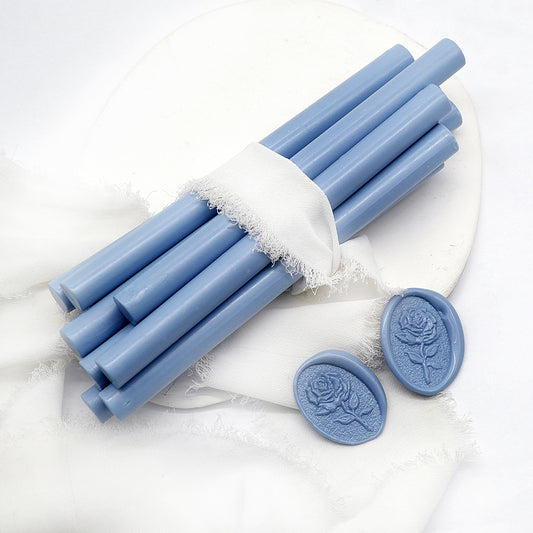 Sealing Wax Sticks in dusty blue with white wedding packing cloth wrapped, beside them, two rose flower pattern wax seals samples created.