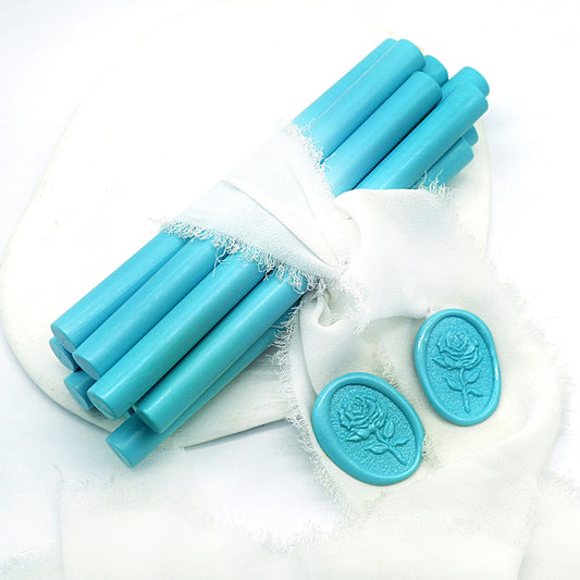Sealing Wax Sticks in turquoise with white wedding packing cloth wrapped, beside them, two rose flower pattern wax seals samples created.