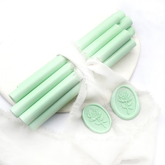 Sealing Wax Sticks in light mint green with white wedding packing cloth wrapped, beside them, two rose flower pattern wax seals samples created.