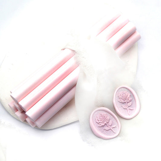 Sealing Wax Sticks in blush pink with white wedding packing cloth wrapped, beside them, two rose flower pattern wax seals samples created.