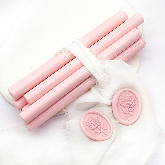 Sealing Wax Sticks in baby pink with white wedding packing cloth wrapped, beside them, two rose flower pattern wax seals samples created.