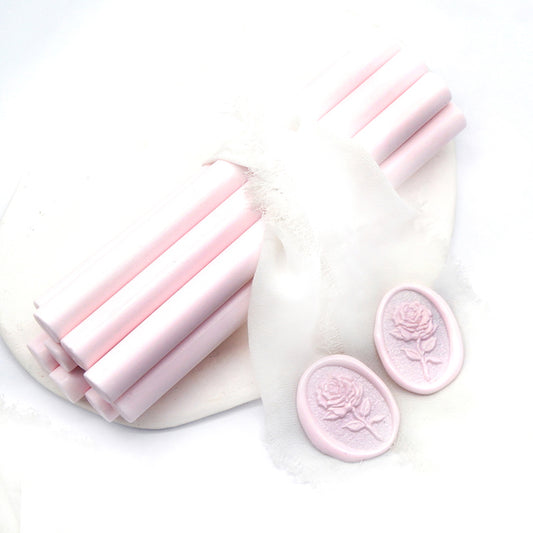 Sealing Wax Sticks in light pink with white wedding packing cloth wrapped, beside them, two rose flower pattern wax seals samples created.
