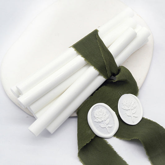 Sealing Wax Sticks in white with dark green wedding packing cloth wrapped, beside them, two rose flower pattern wax seals samples created.