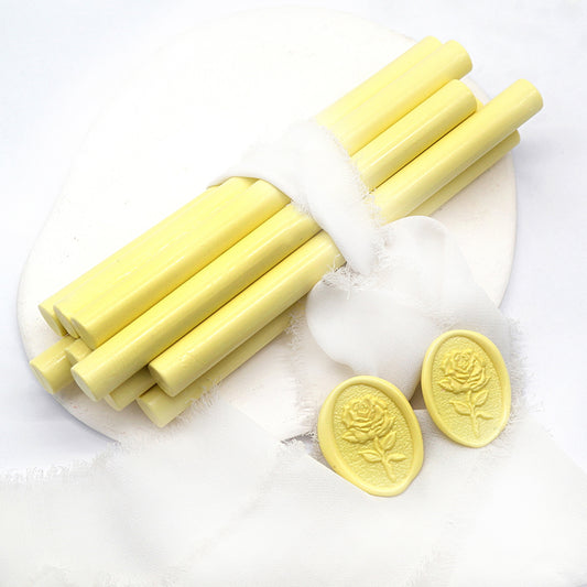 Sealing Wax Sticks in light yellow with white wedding packing cloth wrapped, beside them, two rose flower pattern wax seals samples created.