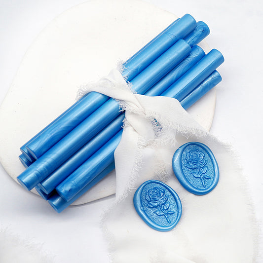 Sealing Wax Sticks in Pearlescent Ocean Blue with white wedding packing cloth wrapped, beside them, two rose flower pattern wax seals samples created.