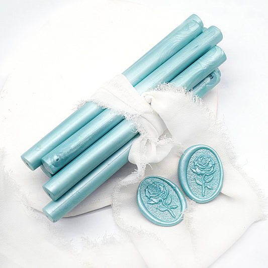 Sealing Wax Sticks in aqua blue with white wedding packing cloth wrapped, beside them, two rose flower pattern wax seals samples created.