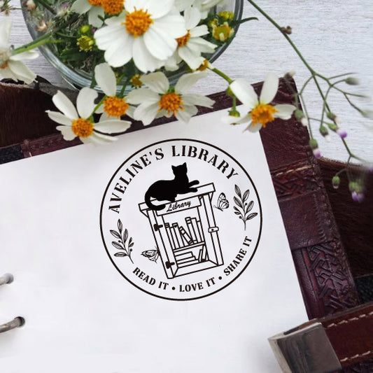 A personalized book stamp in round, surrounded with your name of library and Read It Love It Share It, the centre is the graphic of leaves and butterflies, black cat and bookshelf.