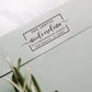 A personalized self inking address stamp, customized with your shop name and address, stamped on the gray envelope.