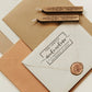 A personalized self inking return address stamp, customized with your shop name and address, stamped on the white envelope to save your time of hand writing, beside it, sealing wax is creating a wax seal on the mail.