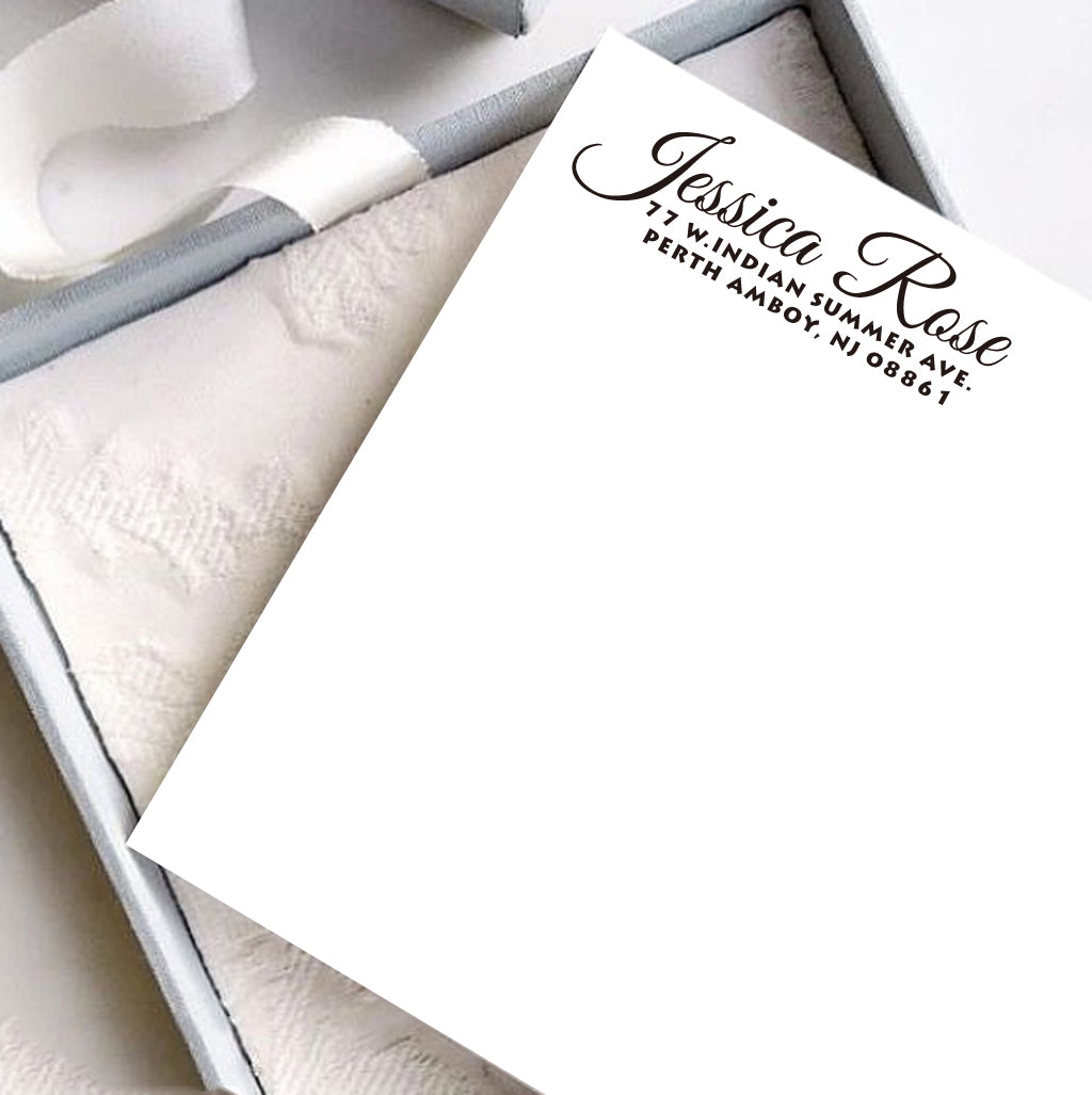 A personalized self inking address stamp, customized with your name and address, stamped on the white card, a gift box is under it.