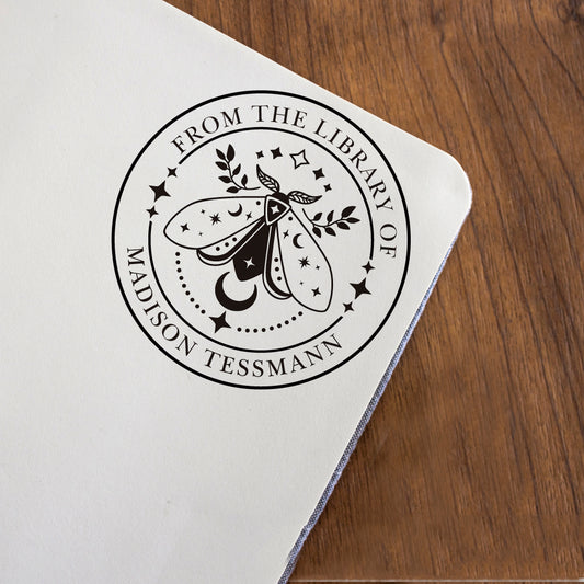 A custom Library Stamp, personalized with your name, moth, stars and leaves pattern, stamped in black on the favorite page on the book.