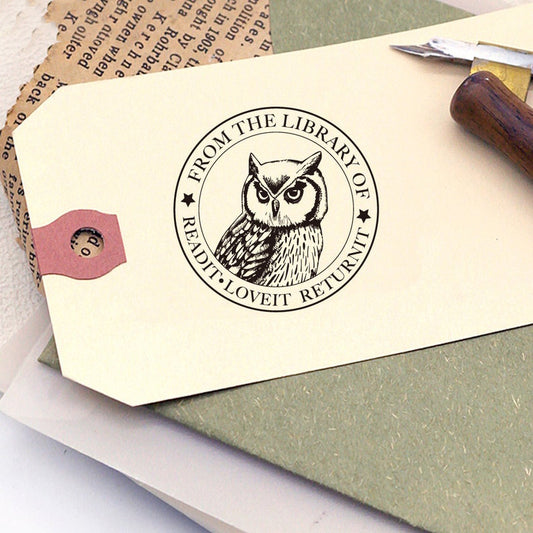 A personalized book stamp, shaped like round, the center is graphic of owl, surrounded with words from the library of and read it. love it. return it. 