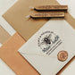 A personalized self inking return address stamp, customized with your name and address, bee and flower, stamped on the white envelope, beside it, sealing wax is creating a wax seal on the mail.