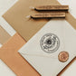 A personalized self inking return address stamp, customized with your name and address, bee and flower, stamped on the white envelope, beside it, sealing wax is creating a wax seal on the mail.