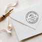 A personalized self inking address stamp, customized with your name, address and mountain, stamped on the white envelop, beside it, a ribbon is waiting for packing the gift.