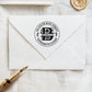 A personalized self inking wedding address stamp, customized with your name, address, initial and leaves, stamped on the white envelope, beside it, a wax seal is waiting for sealing the mail.