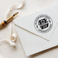 A personalized self inking address stamp, customized with your name, initial, address and leaves, stamped on the white envelop, beside it, a ribbon is waiting for packing the gift.