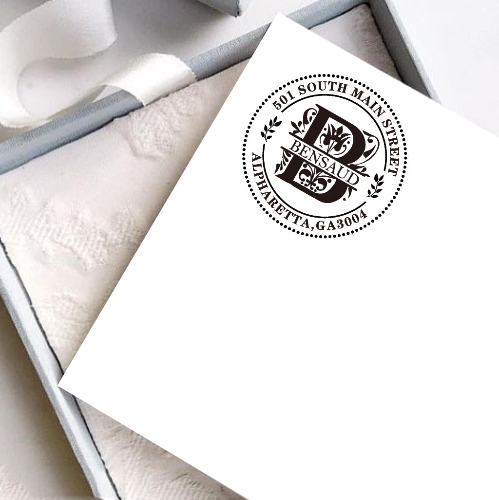 A personalized self inking address stamp, customized with your name, initial, address and leaves, stamped on the white card, a gift box is under it.