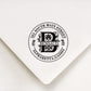 A personalized self inking address stamp, customized with your name, Initial, leaves and address, stamped on the white envelope.