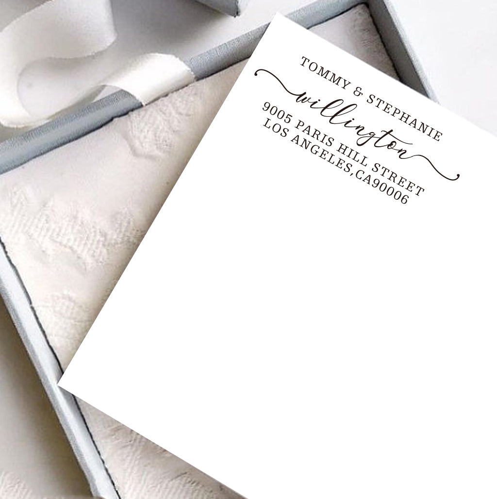 A personalized self inking address stamp, customized with your name and address, stamped on the white card, a gift box is under it.